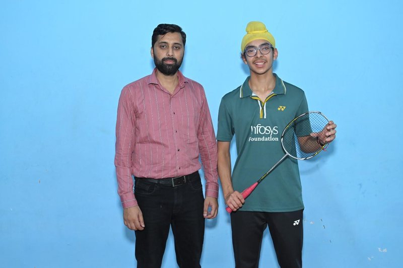 Jagsher Singh holding a racket beside Coach Suresh Kumar against a blue wall